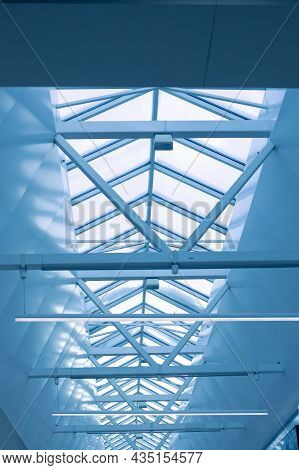 Steel Frame Of The Glazed Roof Of A Warehouse, Shopping Or Office Center Against A Blue Sky. The Cei