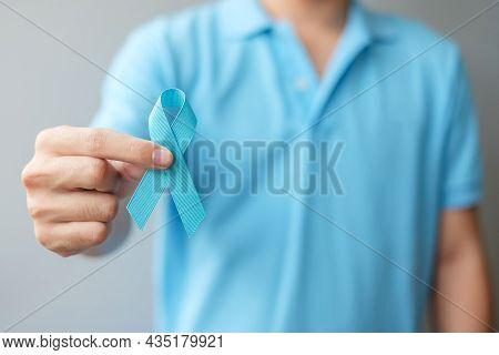 November Prostate Cancer Awareness Month, Man In Blue Shirt With Hand Holding Blue Ribbon For Suppor