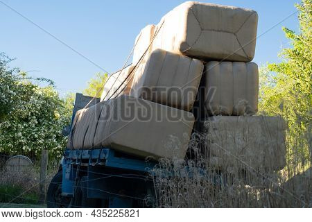 A Large Blue Truck With A Lot Of Cargo, Carrying Several Large Packages. It Is Located On The Side O