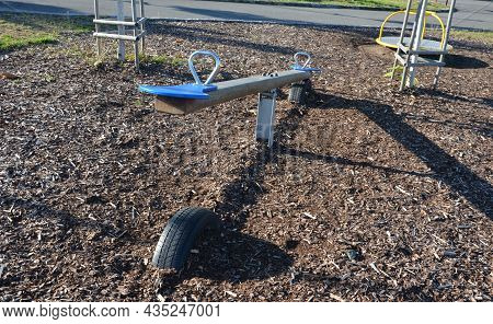 Swing With The Center In Balance. Two Seats For Two Children, Which Alternately Bounce Off The Groun