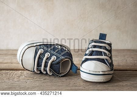 Small Boots On A Wooden Floor, Baby's First Steps, Cute Sneakers For A Baby - A Symbol Of Motherhood