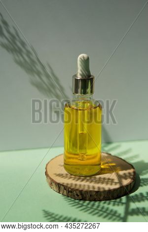 Cosmetic Bottle With Hair Oil On A Wooden Podium. The Concept Of Zero Waste And Ecology. A Hard Shad