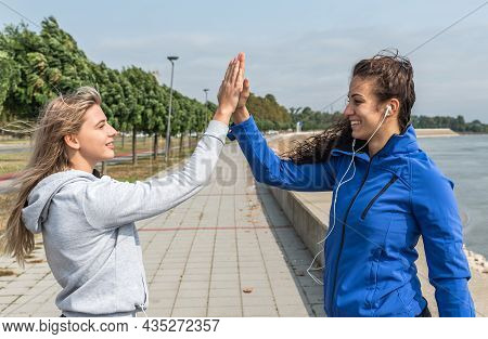 Two Happy Attractive Young Sportswomen Giving High Five After Successful Training. Sportswomen Relax