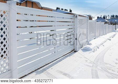 Sliding Plastic Gates For The Entrance Of A Car In A Suburban Village. Car Tracks On A Snowy Road
