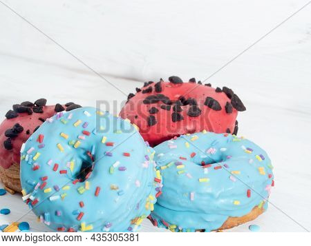 Red And Blue Cronuts On A White Wooden Background. High Quality Photo
