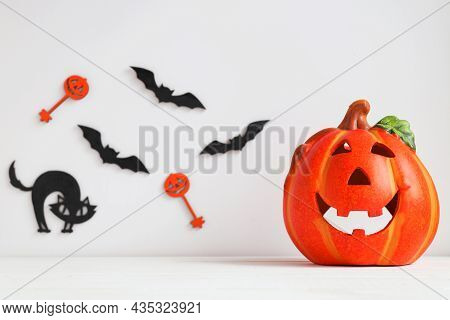 Halloween Card With Pumpkin Or Jack-o-latern, Black Cat And Bats On The Background. Selective Focus