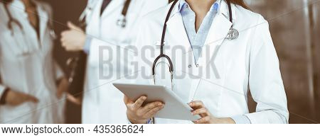 Unknown Woman Doctor Iusing Tablet Computer In Her Hands, While Standing In Clinic. Medicine Concept