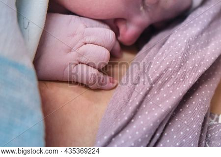 Hand Of A Newborn Baby Close-up. Laying The Child Out On The Mother Chest Immediately After Childbir