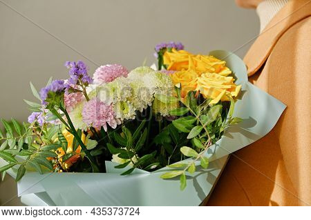 A Woman In A Beige Coat Holds A Beautiful Autumn Bouquet In Her Hands. Depersonalization Concept. Cl