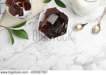 Delicious Grass Jelly Cubes, Milk And Green Leaves On White Marble Table, Flat Lay. Space For Text
