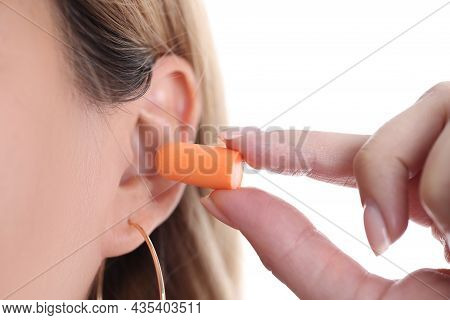 Woman Inserts Soft Orange Earplugs Into Ear Closeup