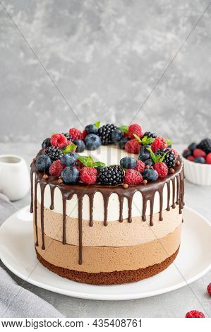 Three Chocolate Mousse Cake With Chocolate Glaze, Blueberries, Raspberries And Blackberries On Top O