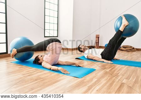 Mature hispanic couple doing excersice and stretching at yoga room. Two adult people doing pilates and flexibility workout