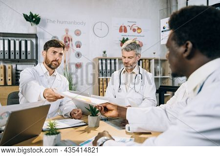 Group Of Multi Ethnic Doctors In Uniform Having International Training At Office Room With Gadgets A
