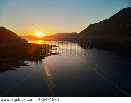 The Western Shore Of Lake Teletsky Is Set At Sunset, The Setting Sun Tingles White Cumulus Clouds Or