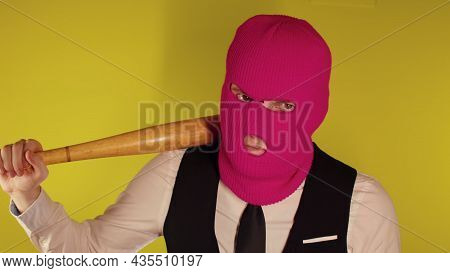 Man In Pink Balaclava With Baseball Bat. Hooligan In Mask With Bat In Hands. A Man In A Business Str