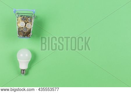Top View To Mini Shopping Trolley With Euro Coints And Light Lamp Bulb On Light Geen Background. Ele
