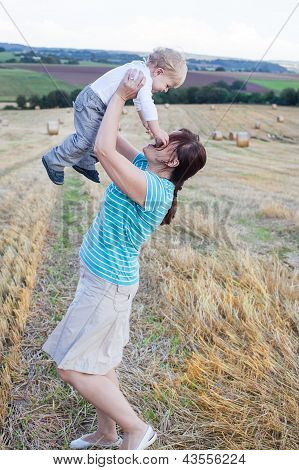 Junge Mutter und ihr kleiner Sohn Spaß Stroh auf dem Gebiet