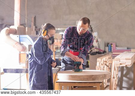 Experienced Carpenter Teaching Young Apprentice At Workshop