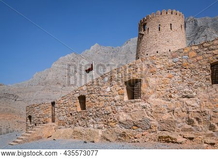 Stone Walls Of Small Medieval Arabian Fort Under Tall Mountain Cliffs. Fortress In Bukha, Musandam P
