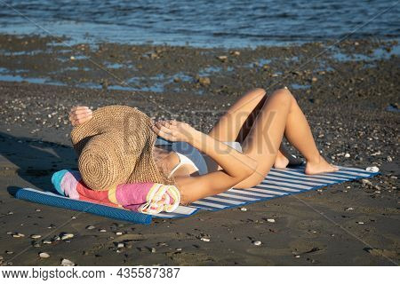 Young Unrecognized Caucasian Woman Wearing A Hat Reasting On The Beach. Summer Vacations, Relaxing O
