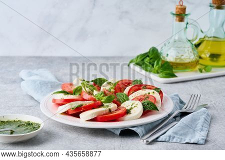 Horizontal Of Italian Caprese Salad With Pesto Sauce. Fresh Mozarella, Sliced Tomatoes, Basil Leaves