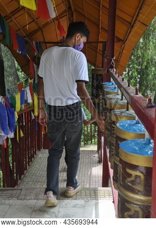 Back View Of A Young Guy Wearing Face Mask With Turning Buddhist Prayer Wheel In Tso-pema