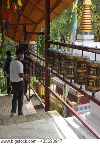 Back View Of A Young Guy Wearing Face Mask With Turning Buddhist Prayer Wheel In Tso-pema
