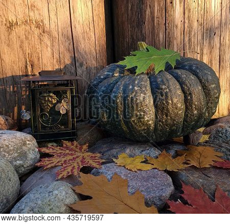 Green Pumpkin And Lantern On The Stones Among The Foliage Against The Background Of An Old Wooden Fr