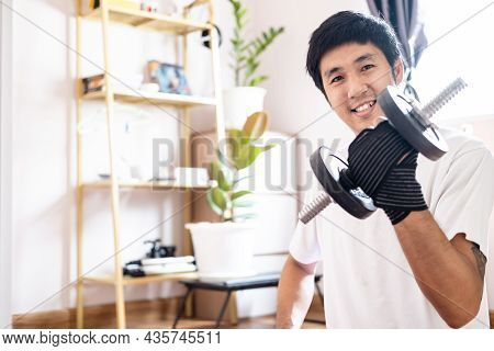 Asian Caucasian Man Hold Dumbbell In Home Training Exercise Bodyweight Trainer Indoors Workout Sport