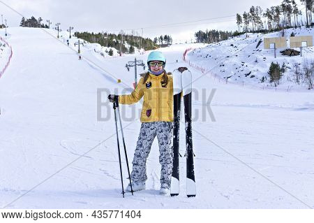 Happy Smiling Young Woman In Yellow Jacket And Ski Helmet Skiing On A Mountain Slope, Winter Sports,