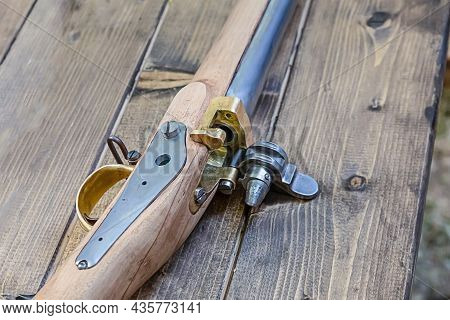 Ancient Weapons With An Iron Barrel And A Wooden Butt On An Old Table