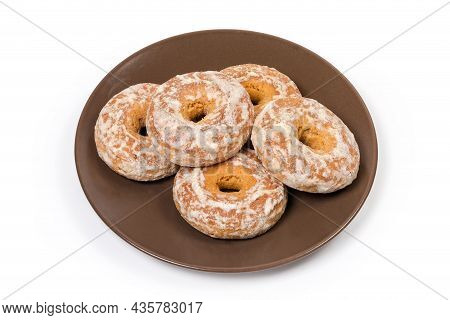 Spice Cookies In The Form Of Rings Glazed With Icing Sugar On A Brown Dish On A White Background