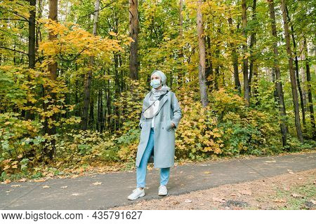 Muslim Woman With Hijab Is Wearing Face Mask Outdoors. Space For Advertisement.