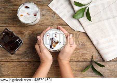 Woman Holding Glass Of Milk With Delicious Grass Jelly At Wooden Table, Top View
