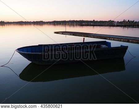 A Boat On A Leash Near The Pier On Lake Palic, Serbia. Sunset On The Pond. Fishing Trip. Calm Water 