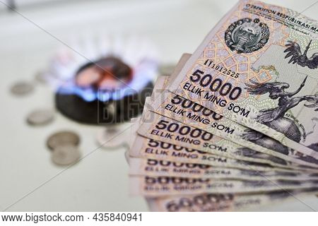 Burning Gas Stove Burner And Uzbek Money - Sum Banknotes. Pay For Natural Gas, Bill, Tariff. Growing