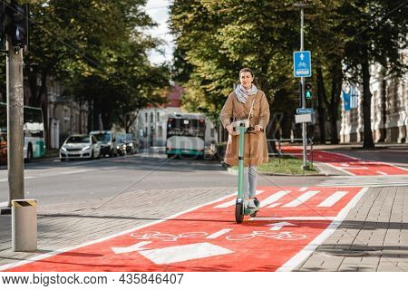 traffic, city transport and people concept - woman riding electric scooter along red bike lane with signs of bicycles and two way arrows on street