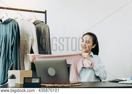 Young Asian Entrepreneurs Are Picking Up Shirts To Compare Proportions For Customers To View Them On