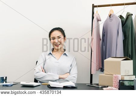 Asian Entrepreneur Sits On A Chair And Smiles, Showing Confidence.
