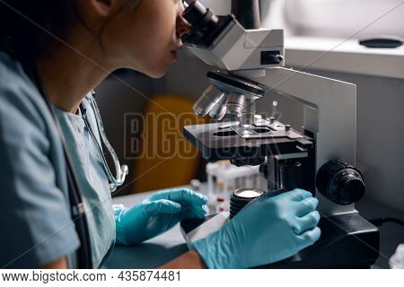 Skilled Lab Employee In Latex Gloves Reaserches Sample Looking Into Microscope In Laboratory