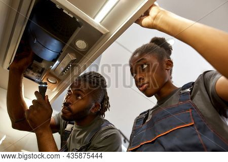 Young Unexperienced Electricians Female Apprentice Watching Professional Work Of Her Mentor. African