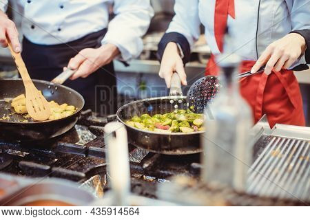 Two diligent chefs working in a hot kitchen cooking delicious food