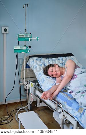 Smiling Woman On Clinic Bed With Anesthesia During Labor Pains. A Pregnant Woman Gives Birth In A Ho