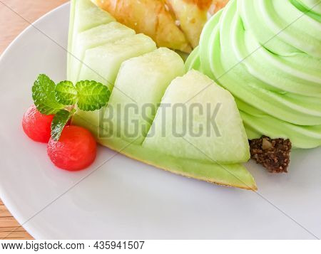 The Green Cantaloop Ice Cream With Two Small Pieces Of Watermelon On The White Dish
