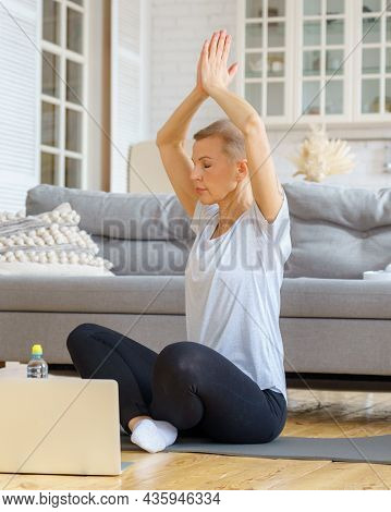 Senior Woman Spending Time At Home, Online Training In Living Room. Exercising With Laptop Watching 