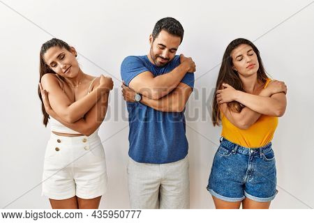 Group of young hispanic people standing over isolated background hugging oneself happy and positive, smiling confident. self love and self care 