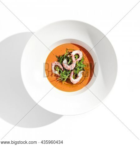 Summer Spanish soup gazpacho with shrimp and rocket salad isolated on white background. Healthy cold tomato soup with prawns. Clean eating for diet.Healthy food in restaurant menu. Seafood gazpacho