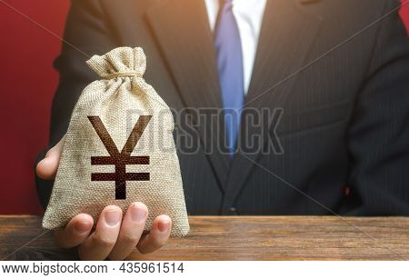 Man Gives A Chinese Yuan Or Japanese Yen Money Bag. Loan Issuance. Financial Support, Leasing. Earni