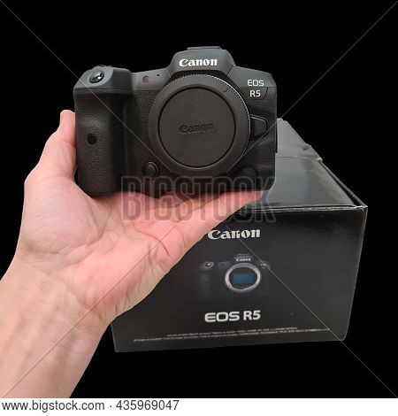 Close Up View Of Hand Holding New Canon Eos R5 Camera Near Package Box On Black Background. Sweden. 